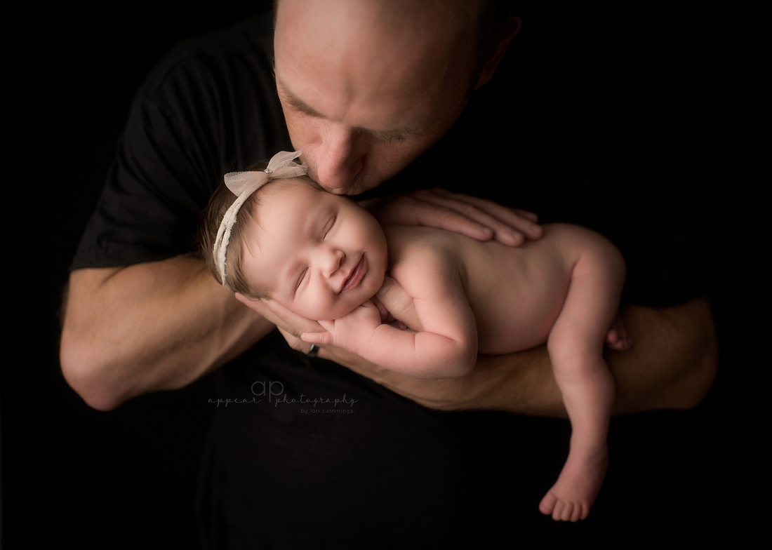 Appear Photography, Hoover, Birmingham, Alabama newborn baby photographer, daddy and daughter, daddy and me, father and child, smile, kiss, black background, daddy kissing baby